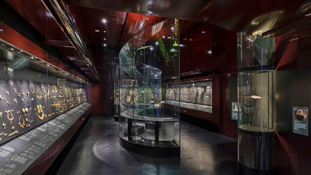 The William and Judith Bollinger Gallery, featuring low lighting and display cases full of jewellery.