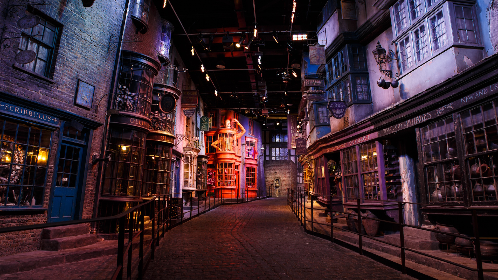 Head to Warner Bros. Studio London - The Making of Harry Potter. Image courtesy of Golden Tours. The set of Diagon Alley at the Warner Bros. Studio Tour in London, featuring empty and darkly lit alleyway with brick buildings and a red facade in the distance.