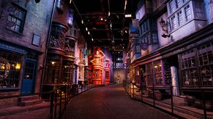 The set of Diagon Alley at the Warner Bros. Studio Tour in London, featuring empty and darkly lit alleyway with brick buildings and a red facade in the distance.