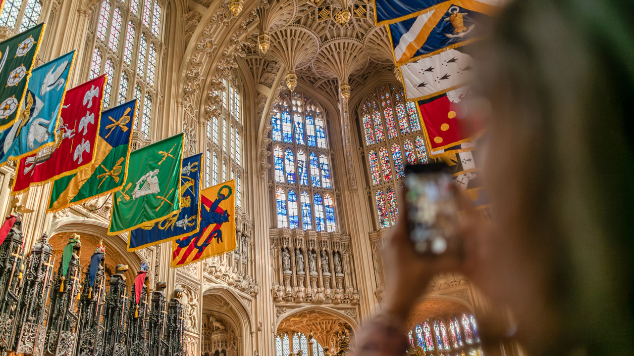 Une femme prend une photo avec son téléphone portable de la chapelle Lady avec son plafond sculpté et ses vitraux.