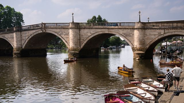 The elegant Richmond Bridge over the river Thames on sunny day with boats on the riverside