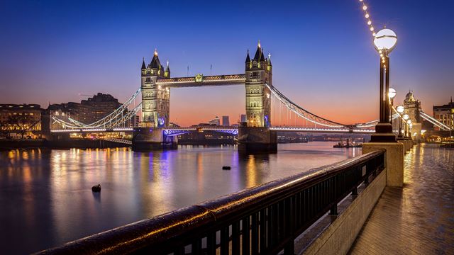 Tower Bridge lit up at night from the riverside