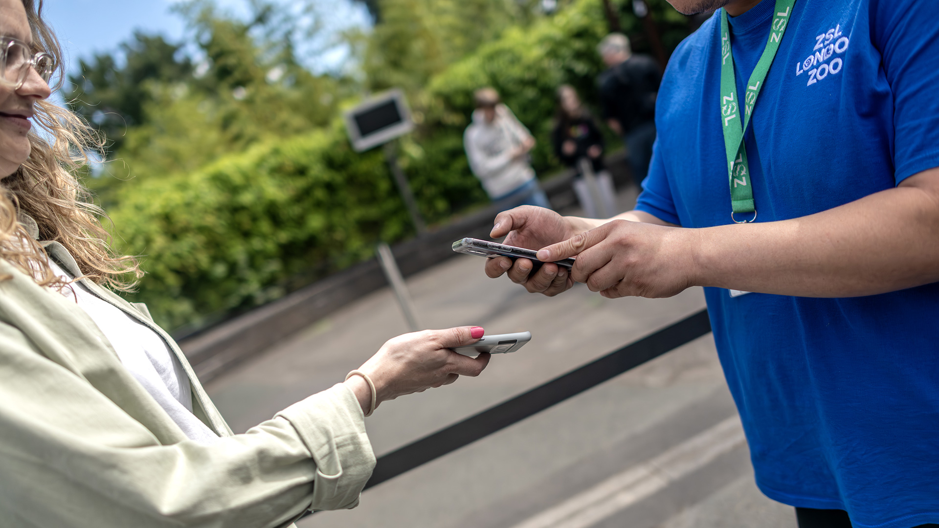 A woman has her London Pass scanned on her smartphone by an attenant wearing a London Zoo polo shirt.