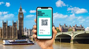A graphic showing person's hand holding up a mobile phone displaying The London Pass on the screen. Big Ben and the river Thames are in the background.
