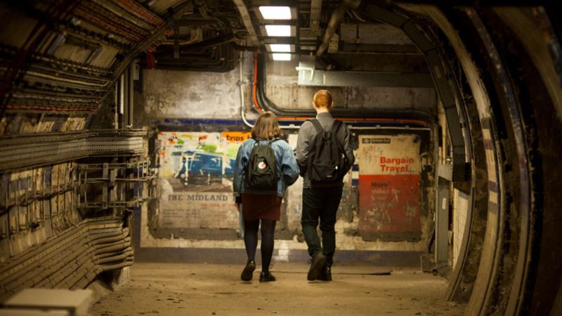 Discover the secrets of London’s Underground with a Hidden Tube tour. Image courtesy of Golden Tours. Two people standing in the centre of an underground tunnel on a tube tour.
