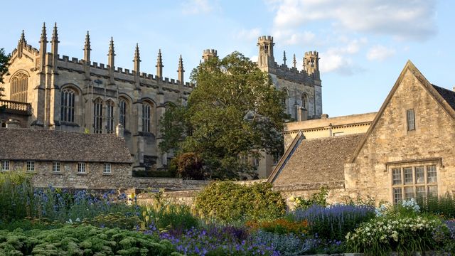 Un grand bâtiment historique entouré d'arbres dans la prairie de Christ Church à Oxford.