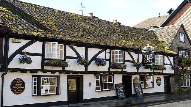 Landscape image of an old inn, which charming thatched roof, wooden beams, white walls and traditional window panes.