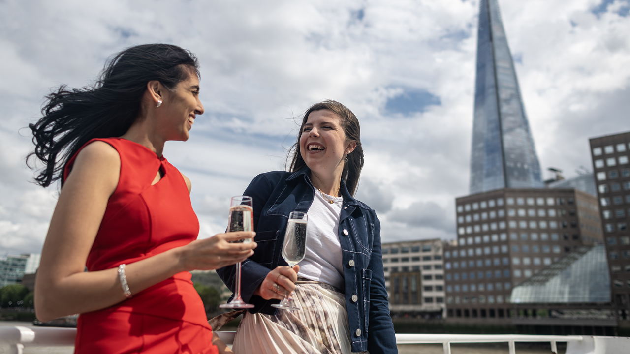 Echappez à la foule et profitez d'un afternoon tea alors que vous naviguez le long de la Tamise à bord d'un des bâteaux City Cruises de Londres. © London & Partners/Michael Barrow Deux femmes profitent d'un verre de périllant à bord de la croisière spécial afternoon tea City Cruises de Londres passant près du Shard.