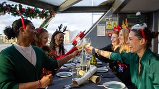 A crowd of people wearing festive costumes enjoying a Christmas Day lunch aboard a cruise.