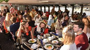 A crowd of people wearing festive costumes enjoying a Christmas Day lunch aboard a cruise.