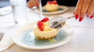 A blue and white plate with a vanilla cheesecake and strawberrys.
