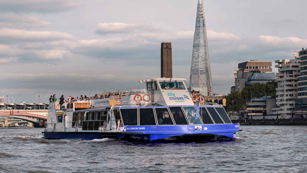 Profitez d'une excursion d'une journée sur la Tamise avec City Cruises et traversez Londres à toute vitesse. ©City Cruises- crédit photo : Christopher Ison Le bâteau de croisière touritsique City Cruises navigue le long de la Tamise avec vue sur le Shard à l'arrière plan.