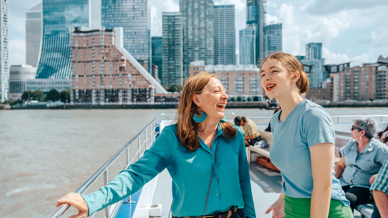 Explorez Londres à votre rythme grâce au pass à la journée de City Cruises. ©London & Partners/Michael Barrow Deux femmes rigolent depuis le pont ouvert de l'un des bâteaux croisières de City Cruises navigant le long de la Tamise à Londres.