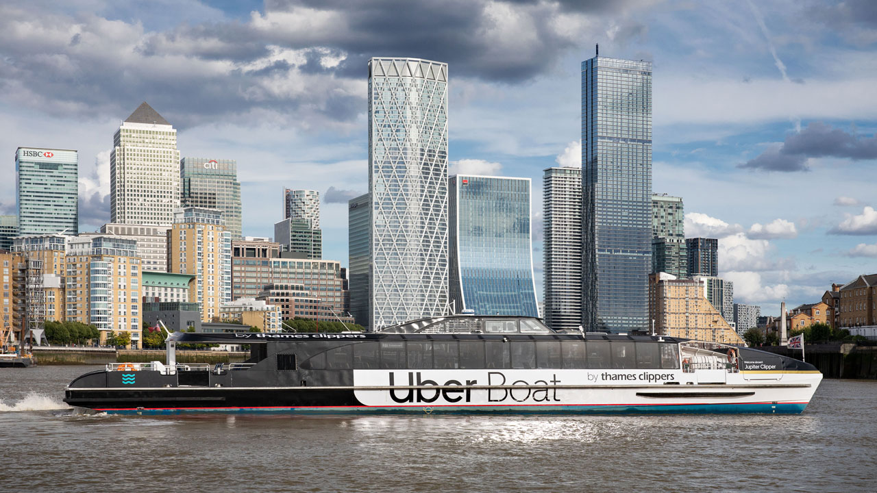 Montez à bord d'un bateau Uber Thames Clipper et admirez Londres depuis la rivière avec des panoramas inégalés. ©Uber Boat par Thames Clippers Un bateau Uber Boat navigue la Tamise, et passe devant le quartier finacier de Canary Wharf.