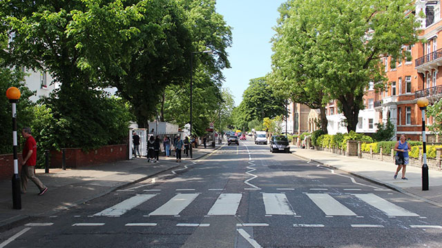 Stellen Sie das legendäre Albumcover der Beatles in der Abbey Road nach. Bild mit Genehmigung von Golden Tours. Der berühmte Fußgängerüberweg vom legendären Albumcover der Beatles in der Nähe der Abbey Road Studios an einem sonnigen Tag