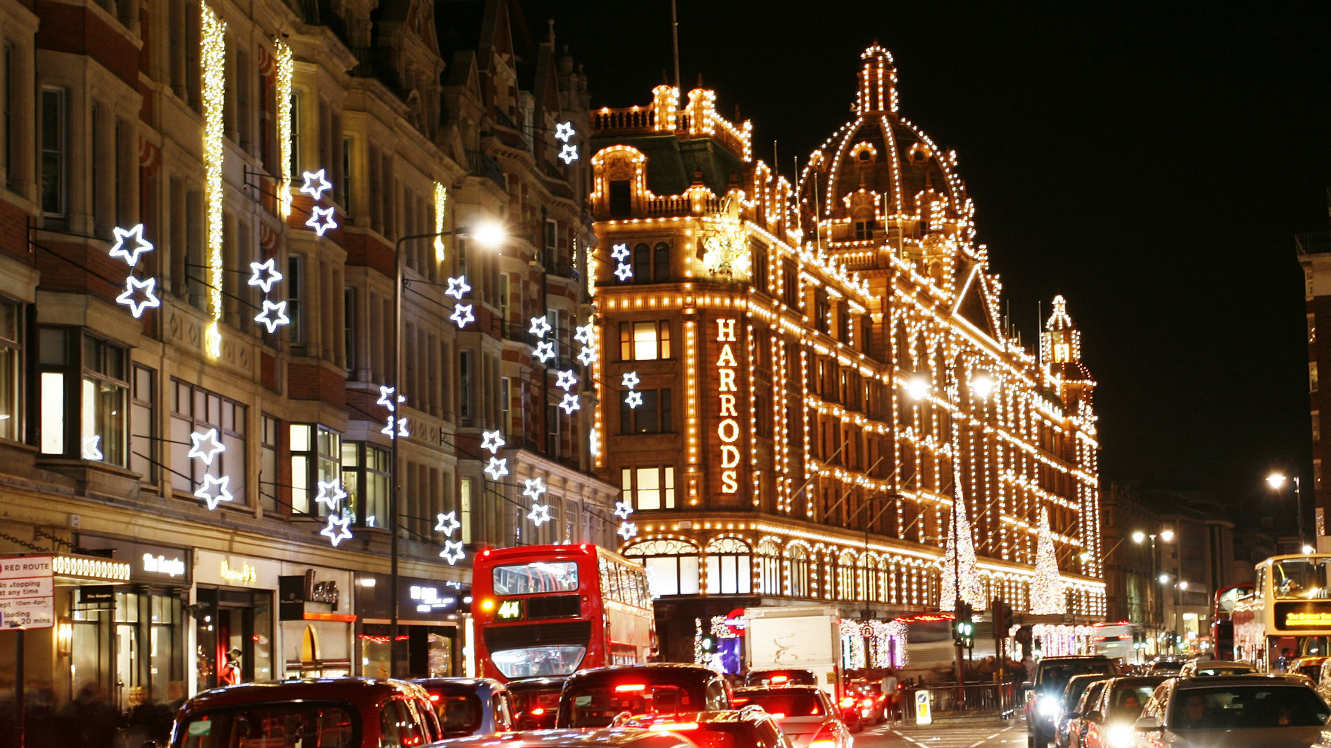 Das Designer-Kaufhaus Harrods, geschmückt mit Weihnachtsbeleuchtung. Bild mit Genehmigung von London & Partners. Foto einer Straße mit dem Kaufhaus Harrods, geschmückt mit Weihnachtsbeleuchtung.