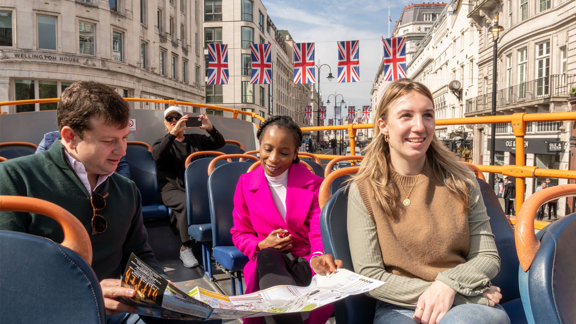 Enjoy the best views of the city from London's hop-on hop-off bus. Image courtesy of London & Partners/Michael Barrow. Group of people on board the top deck of a hop-on hop-off bus.
