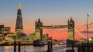 The shard and london bride skyline lit up at night with a stunning sunset backdrop.