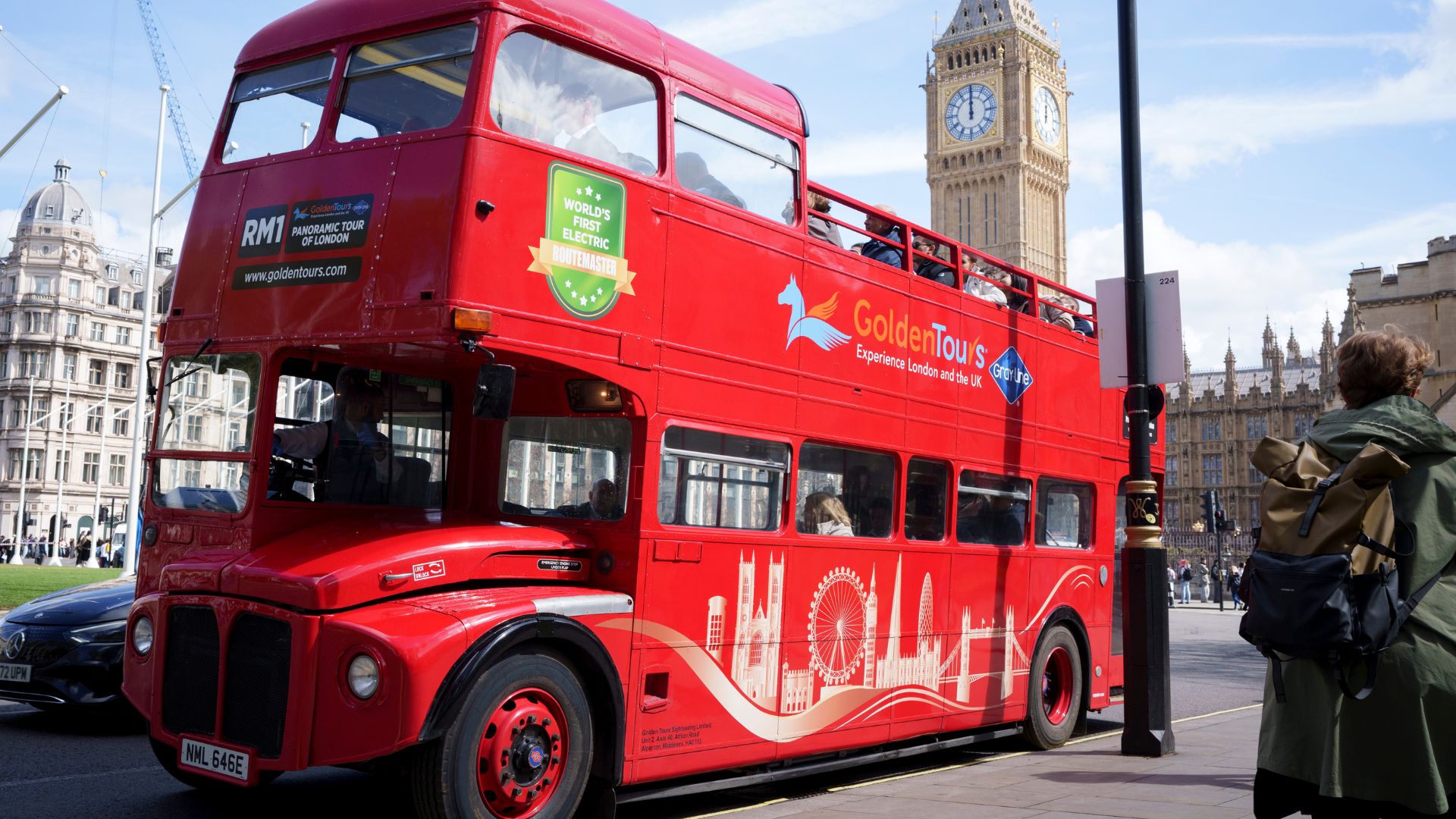Vintage Routemaster bus driving through London with Big Ben in the background.