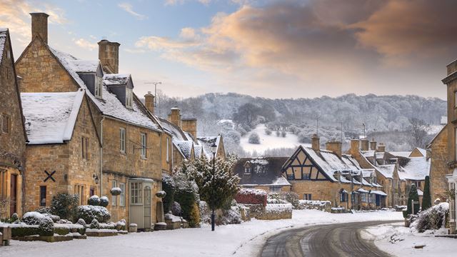 Village in the English Cotwolds with snow-covered thatched cottages. 