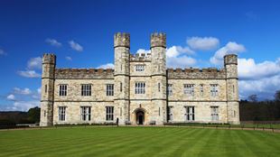 Leeds Castle on a clear day with blue sky and green grass in foreground.