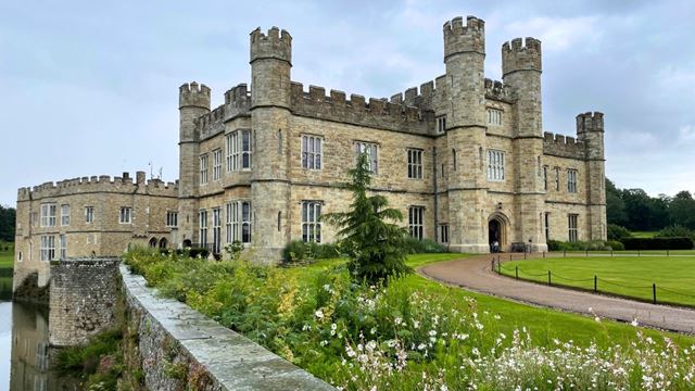 Leeds Castle next to water and blue skies.