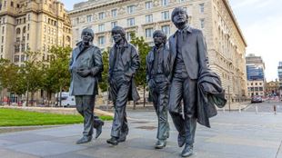 Lifesize statue of The Beatles in the streets of Liverpool on a clear day.
