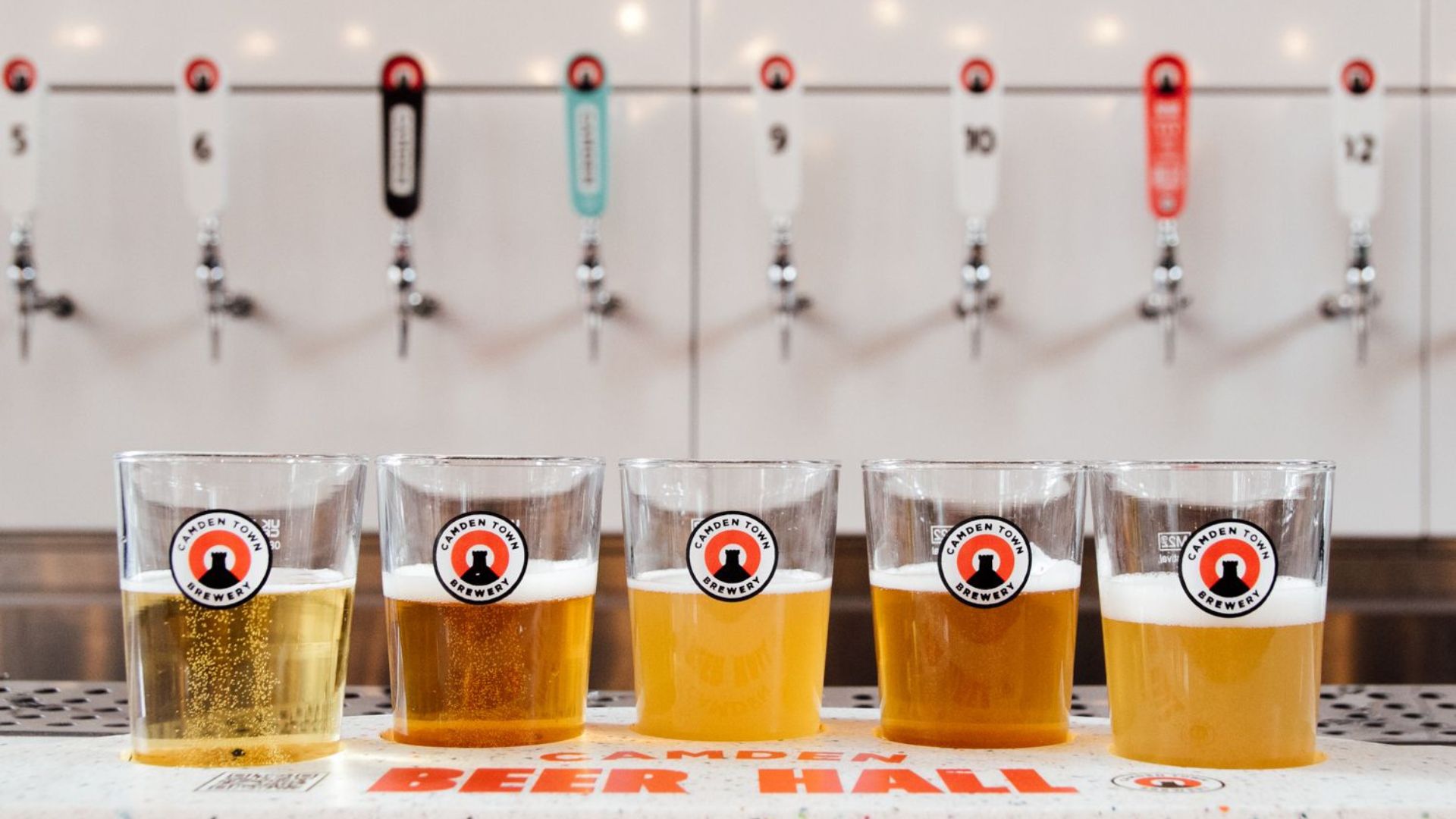 Line-up of beer tasting glasses in front of taps at Camden Town Brewery.