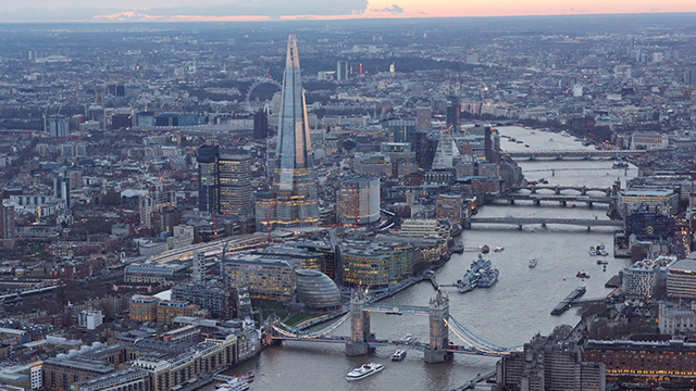 Ein Luftaufnahme des Londoner Stadtzentrums bei Sonnenuntergang, aufgenommen aus dem Hubschrauber, mit der Themse, der Tower Bridge und dem Shard.