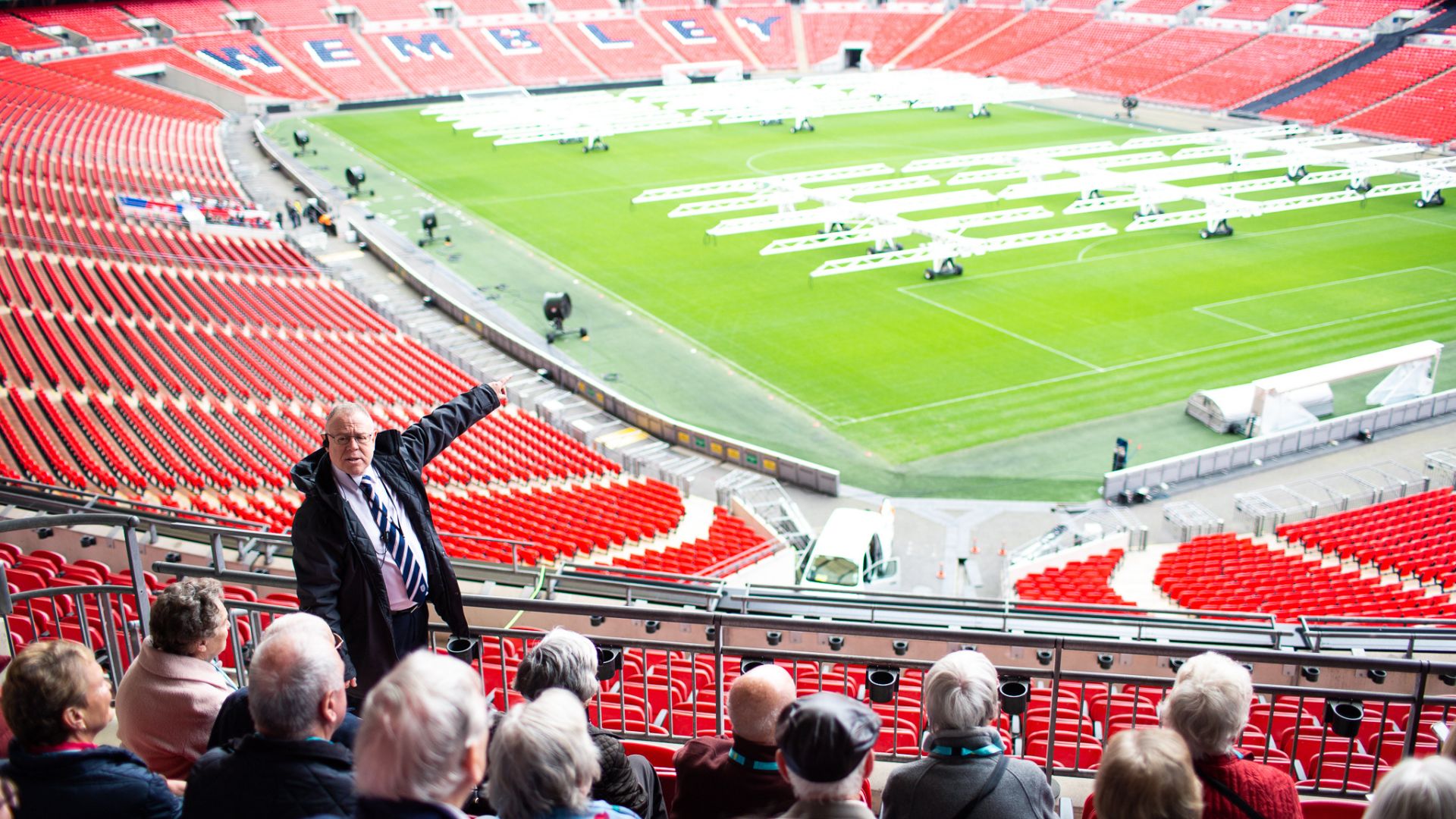 Visitors take part in a guided tour of Wembley Stadium overlooking the pitch and stands.