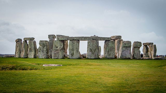 A view of Stonehenge on a bright day from the grassland surrounding the sight.