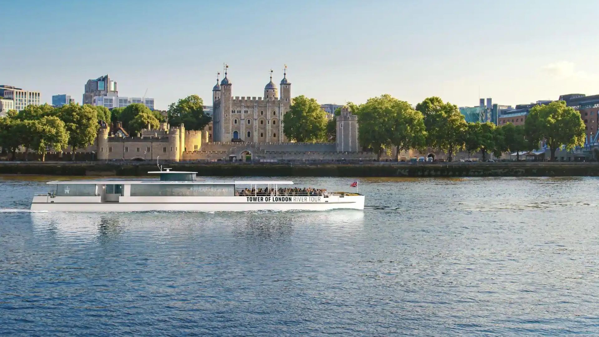 Tower of London River Cruise with white exterior and wide glass windows with the Tower of London in the background.