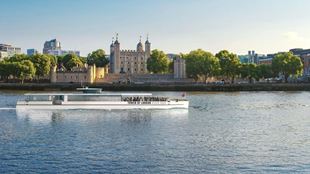 Tower of London River Cruise with white exterior and wide glass windows with the Tower of London in the background.