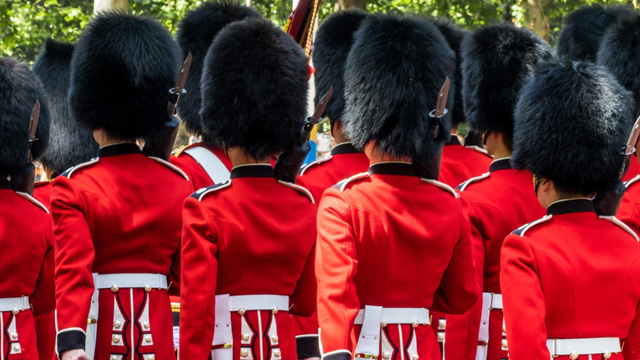 Nimm an der Royal Walking Tour of London teil und entdecke die lange Geschichte der Stadt über die königlichen Familie. Bild mit Genehmigung von Shutterstock. Nahaufnahme der Königsgarde während der Zeremonie der Wachablösung in London. Die Garde trägt die traditionelle rote Uniform und die Bärenfellmütze.