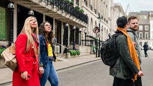 Un groupe de deux femmes et de deux hommes traverse les rues de St James à Londres et observe les monuments et attractions.