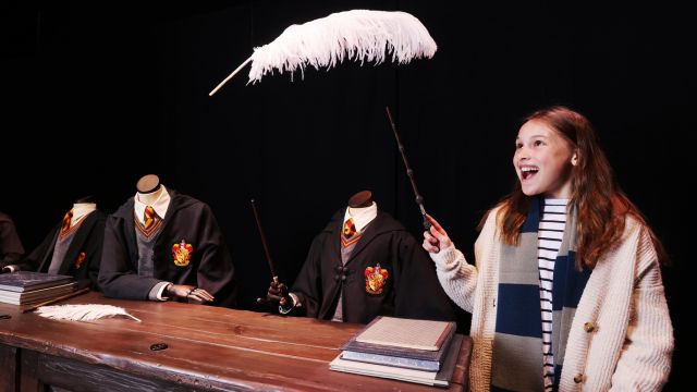 A person uses a wand to cast a spell over a feather at the warner bros studio tour london.