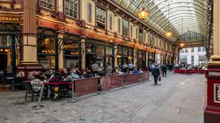 long angle shot of inside Leadenhall Market, with Victorian decor and people sitting outside a pub in the market