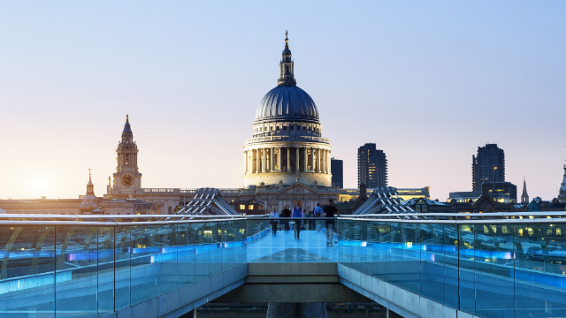 Vue depuis le Millenium bridge, pont menant à la cathédrale St Paul. Photo fournie par Shutterstock. Vue sur le Millenium Bridge illuminé de bleu, la cathédrale St Paul et la City de Londres en soirée.