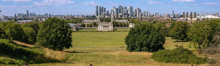 A view of the National Maritime Museum and surrounding city from Greenwich Park on a blue sunny day