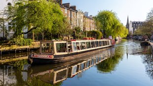 A boat called Gardenia on the river in Little Venice, surrounded by green trees