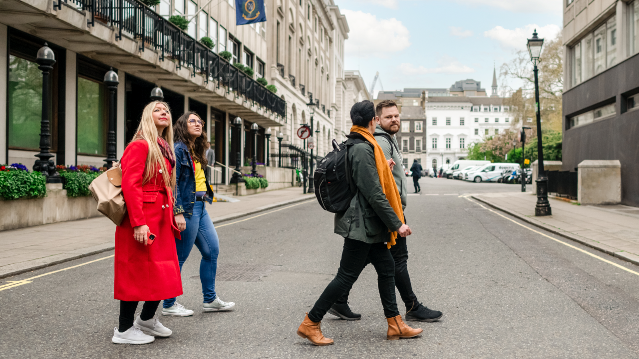 Lernen Sie auf einem Rundgang die Geschichte von London kennen. Bildnachweis: London & Partners/Michael Barrow. Eine Gruppe spaziert auf einer Royal Walking Tour an Gebäuden vorbei.