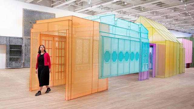 Person walking through colourful installation of houses at Tate Modern.