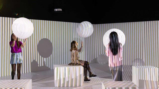 Three installations at Electric Dreams, Tate Modern with three people standing near them.