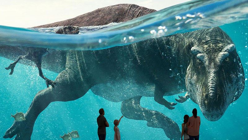 A large projection of a swimming T-Rex at Prehistoric Planet: Discovering Dinosaurs at Lightroom