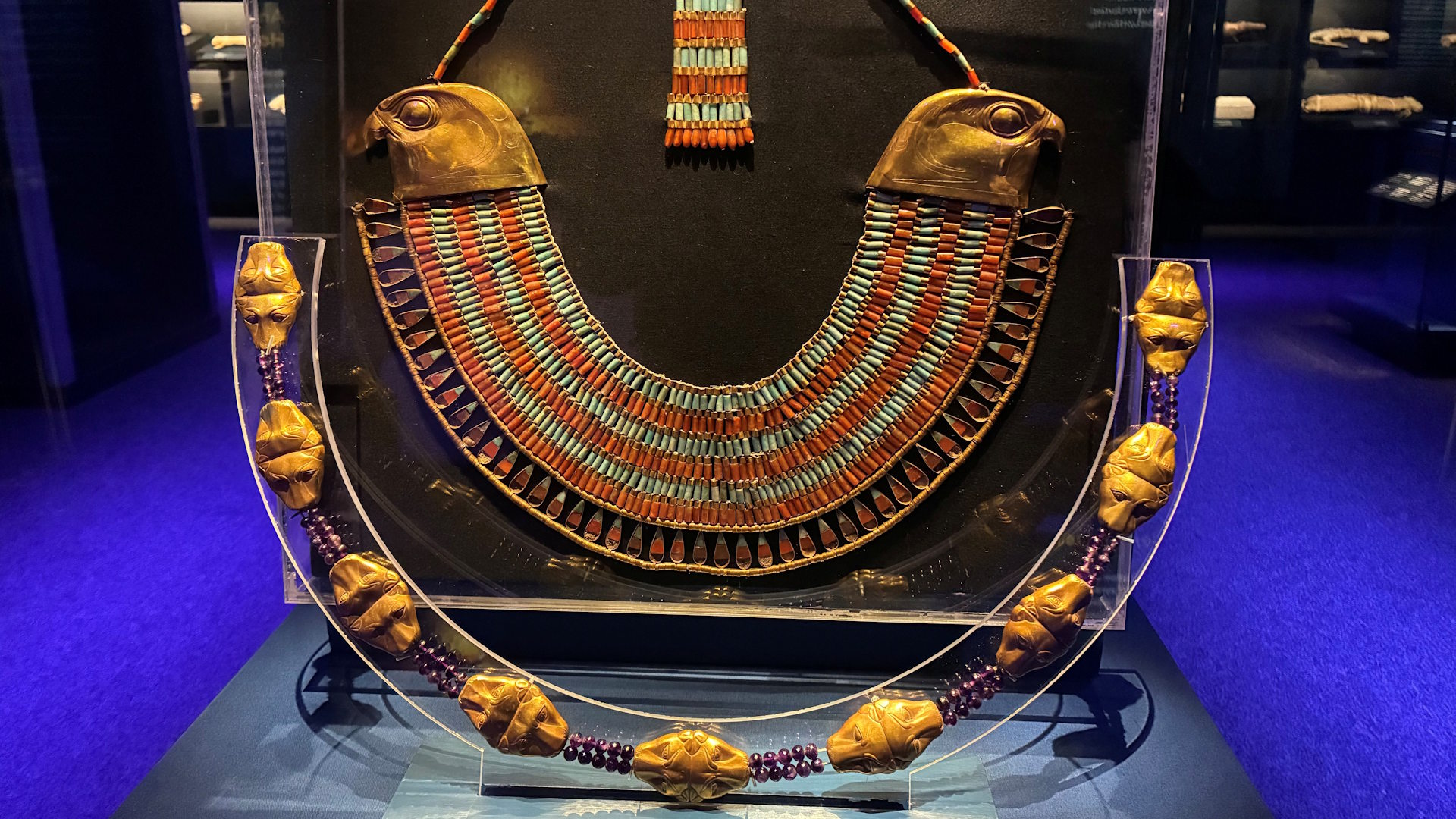 A display of a collar featuring falcon heads and a gold girdle.