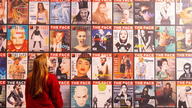 Person looking up at a wall with The Face magazine covers next to each other.