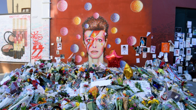 Painted mural of David Bowie in Brixton covered with flowers and letters