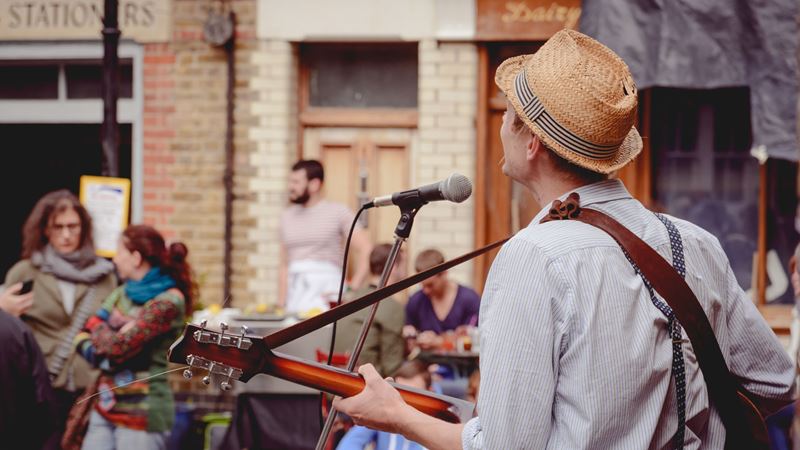 Man busks with his guitar and a microphone on the streets of London