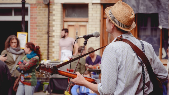 Man busks with his guitar and a microphone on the streets of London