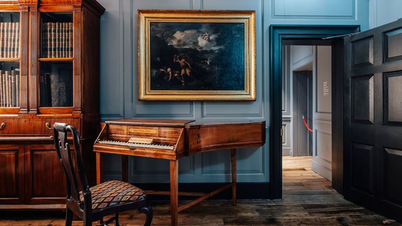Step inside the world of two gifted musicians at Handel & Hendrix in London. Credit: visitlondon.com/Michael Barrow. Image courtesy of London & Partners. A photo inside one of the rooms at Handel and Hendrix in London with a chair in front of a piano, a wooden bookcase and a large gold framed painting on the wall
